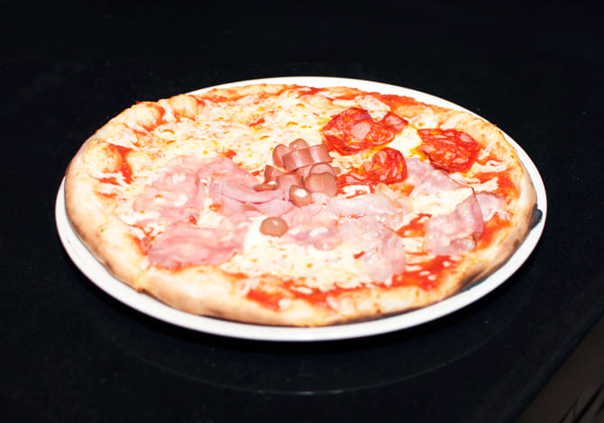 Pizza capricciosa <small>(tomate, mozzarella,  jamón york, alcachofas,champiñones, salchichas, aceitunas negras, aceite y orégano)</small>